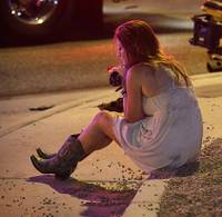Sheri Sletten sits on a curb at the scene of a shooting outside of a music festival along the Las Vegas Strip, Monday, Oct. 2, 2017, in Las Vegas. Multiple victims were being transported to hospitals after a shooting late Sunday at a music festival on the Las Vegas Strip.