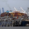 A U.S. flag flies on a moored boat as the container ship Dali rests against the wreckage of the Francis Scott Key Bridge, Tuesday, March 26, 2024, as seen from Pasadena, Md.