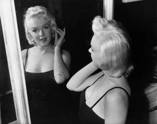 In conference - Actress Marilyn Monroe, film star turned business executive, checks her lines - all curves - in a mirror at the photographic studio of her business partner, Milton Greene, in New York Jan. 28, 1955. 