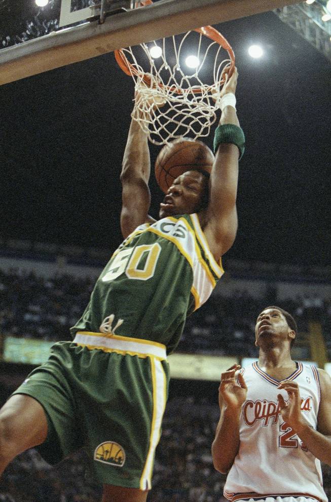 Seattle Supersonics' center Earvin Johnson (50) dunks the ball, Oct. 29, 1994 during the first quarter action at the Palacio de los Deportes in Mexico City.  Four teams are playing tonight and on Saturday in Mexico City. In the background is Los Angeles Clipper's Elmore Spencer.