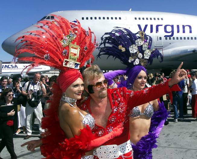 Virgin Atlantic Airlines' Richard Branson, dressed as Elvis Presley, poses with showgirls Pamela Boulden, left, and Kristy Brotherson at McCarran International Airport after Branson arrived on the first Virgin Atlantic nonstop flight from London to Las Vegas on June 8, 2000.