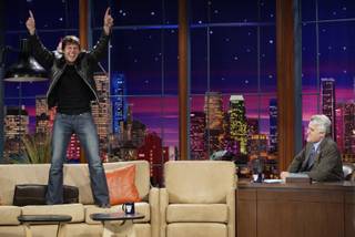In this photo released by NBC, Tom Cruise jumps onto the sofa after greeting host Jay Leno on the set of 