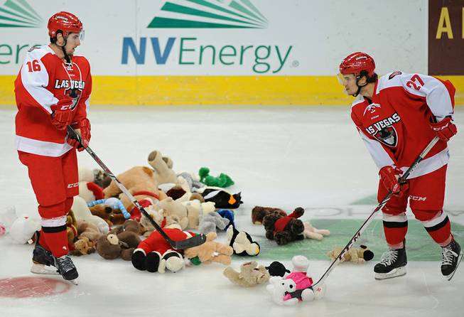 Las Vegas Wranglers players Matt Tassone, left, and Bryce Reddick collect plush animal toys into a pile as they fall to the ice after Tassone scored in the third period against the San Francisco Bulls at the Orleans Arena. All the toys collected will be donated to a local elementary school for the holiday season.