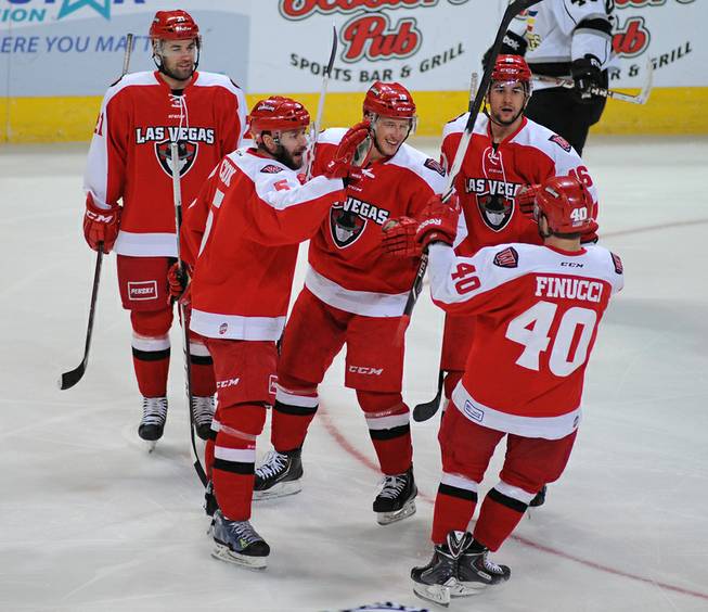 Wranglers forward Adam Hughesman, center, smiles as he is congratulated by teammates after scoring a first period goal, his team-leading 13th of the season, against the Colorado Eagles on Wednesday night.