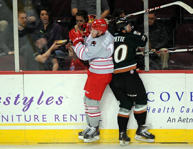 Las Vegas Wranglers defenseman Ryan Forgaard, left, turns to hit Utah Grizzlies forward Danick Paquette against the glass during the second period on Friday night at the Orleans Arena.