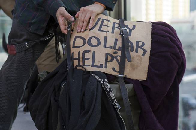A panhandler packs up to leave after soliciting money with a dog on a pedestrian overpass near Planet Hollywood Friday, Dec. 30, 2011. A proposed county ordinance would ban the use of dogs and other animals by people soliciting money on the Strip.