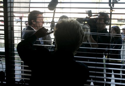 A woman peeks out the window as presidential candidate John Edwards gives an interview during a campaign appearance at the Egg & I restaurant on West Sahara Ave. Tuesday, Jan. 15, 2008.