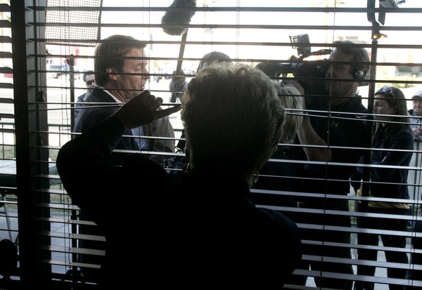 A woman peeks out the window as presidential candidate John ...