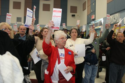 Hillary Clinton supporter and first-time caucaser Betty Frazee raises her card  during the Democratic caucus at Tarr Elementary School.