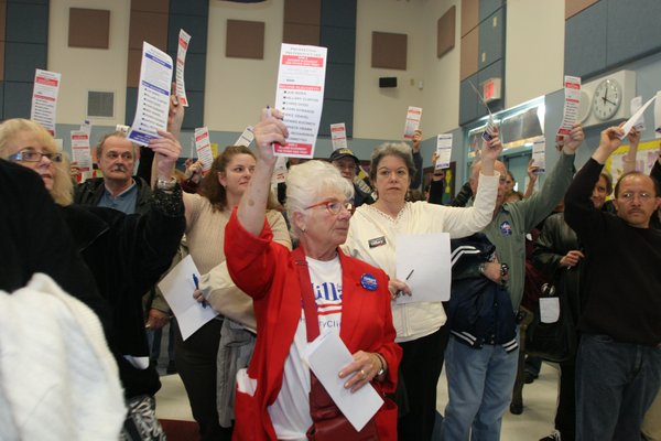 Hillary Clinton supporter and first-time caucaser Betty Frazee raises her ...