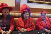 Red Hat Society members, from left, Anita Burchard, Edye Farran and Pat Hickok are gathered in the Cafe at Harrah’s to talk about the upcoming convention, the opening of the musical “Hats!” and a hoped-for record-setting chorus line. 