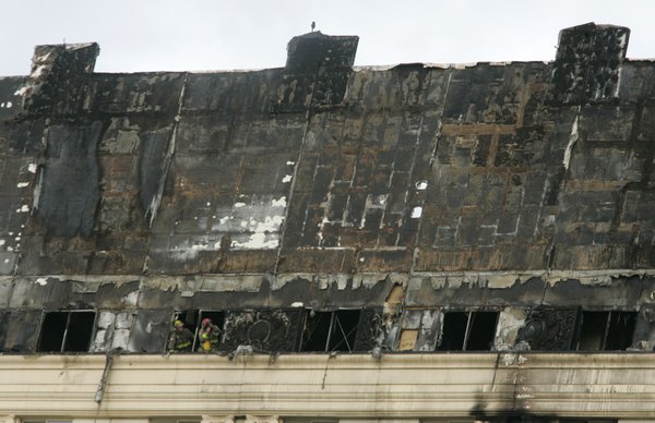 Firemen look out the top floor of the Monte Carlo ...