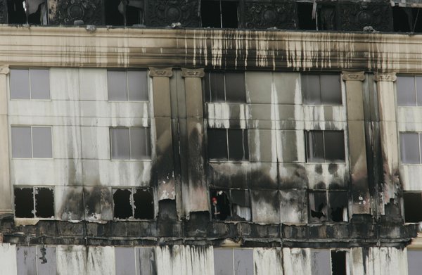 A fire inspector looks out a window on one of ...