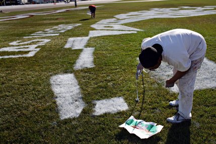 Painting for more than 20 years, Carlos Garcia, looks over the design template before freehand painting a section of the logo on the infield at the Las Vegas Motor Speedway.