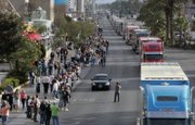 A videographer photographs NASCAR car haulers, the 18-wheelers that transport the race cars and teams to each track as they parade northbound on Las Vegas Boulevard. 