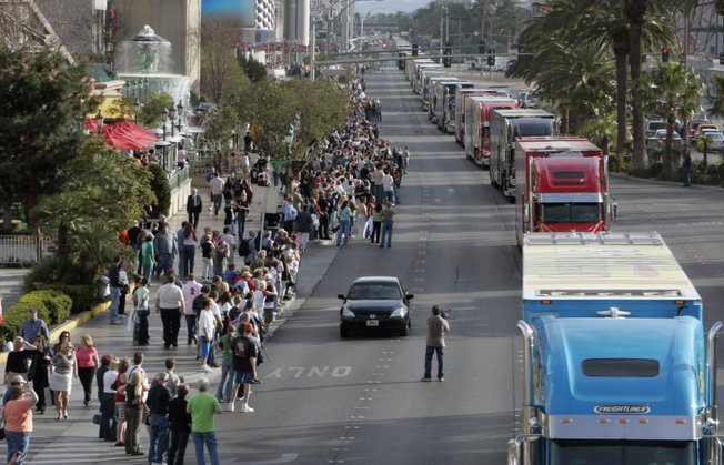 A videographer photographs NASCAR car haulers, the 18-wheelers that transport the race cars and teams to each track as they parade northbound on Las Vegas Boulevard. 