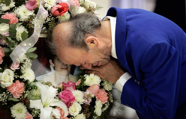 Zyber Selimaj hugs a memorial photo of his wife during ...