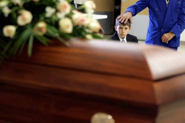Alban Selimaj, 11, looks at his mother's coffin with his ...