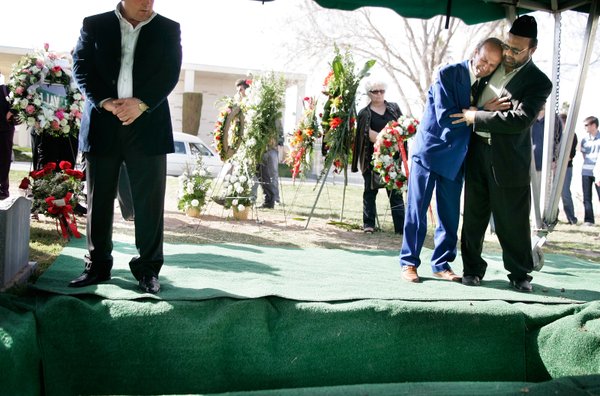 At right, Zyber Selimaj is comforted at the grave site ...