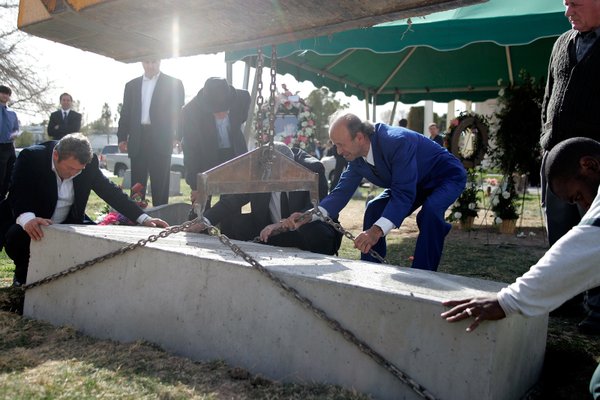 Zyber Selimaj, center, and others help lower a concrete vault ...