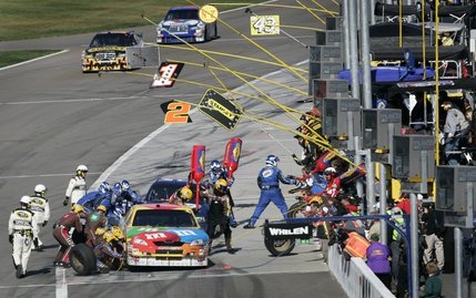 Kyle Busch, foreground, and Kurt Busch get their cars serviced in Pit Row during the NASCAR UAW-Dodge 400.