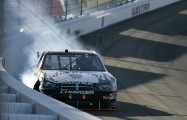 Driver Robby Gordon scrapes against the wall in turn two ...