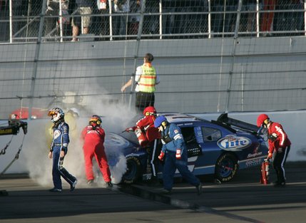 Kurt Busch, left, walks away after losing control and hitting the wall during Sunday’s NASCAR UAW-Dodge 400 auto race at Las Vegas Motor Speedway. Jeff Gordon also was involved in a crash.
