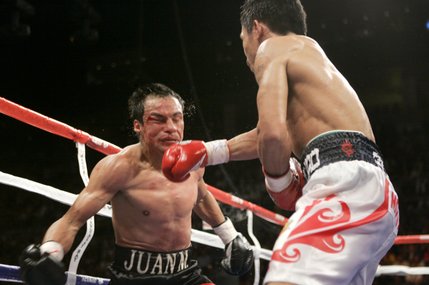 WBC super featherweight champion Juan Manuel Marquez, left, takes a punch from Manny Pacquiao during their title fight Saturday at the Mandalay Bay Events Center, which Pacquiao won. After the bout the fighters’ promoters battled with words.