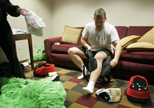 Dave Romleski removes his knee brace after performing in a $12,500 bull suit as The Duke, during a game last year. He says he loses about 10 pounds a game and sweats through a dozen T-shirts.