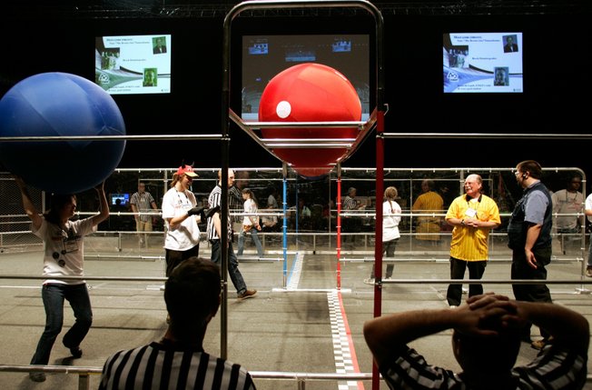 Crew members set up balls the robots have to grasp, hoist and fling while careering like bumper cars around a cage-enclosed 54-by-27-foot track for the competition.