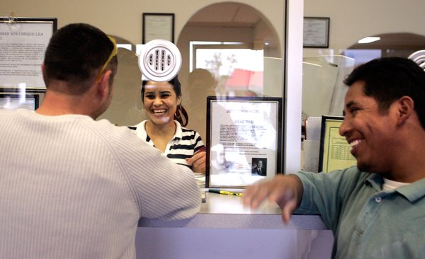 Teller Edith Gonzalez helps Ruben Rios, left, and Ruben Martinez ...