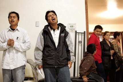 Porfirio Hernandez, from left, and Pascual Martinez sing a prayer during services at Amistad Cristiana church in Las Vegas. Martinez is earning a fourth of what he did a year ago and has moved with his family of five into a trailer the church owns.