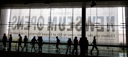 The Newseum's opening day banner is seen through windows as visitors walk the halls during opening day.