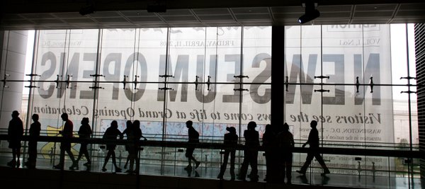 The Newseum's opening day banner is seen through windows as ...
