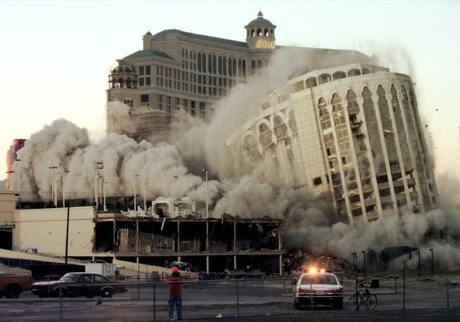 The 31-year-old Aladdin crumbles to the ground on April 27, 1998, while the under construction Bellagio hotel looms in the background. The hotel's implosion cleared the way for the $1.3 billion Aladdin Project. However financial troubles caused the Aladdin to close. The property reopened in November 2007 as the Planet Hollywood Resort and Casino.
