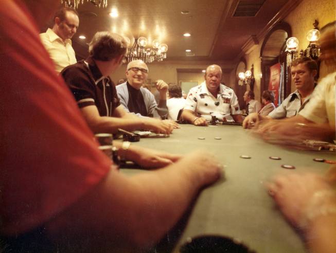 Johnny Moss, wearing glasses, plays a round at the World Series of Poker. Moss is the first player to win two consecutive tournaments, taking the title in 1970 and in 1971. The "Grand Old Man" is also famous for his duel with Nick "The Greek" Dandalos, an east coast high-stakes gambler, who allegedly lost  $4 million in a five month contest with Moss.