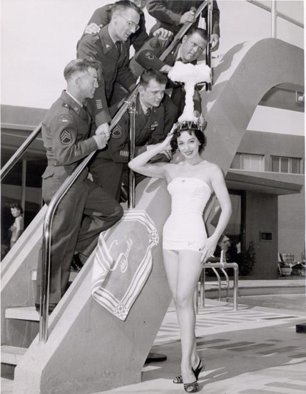 Sands Copa Girl, Linda Lawson, is crowned "Miss-Cue" by military personnel participating Operation Cue at the Nevada Test Site, May 1, 1955. High winds caused Operation Cue to suffer from numerous delays, causing personnel to name it "Operation Miscue."