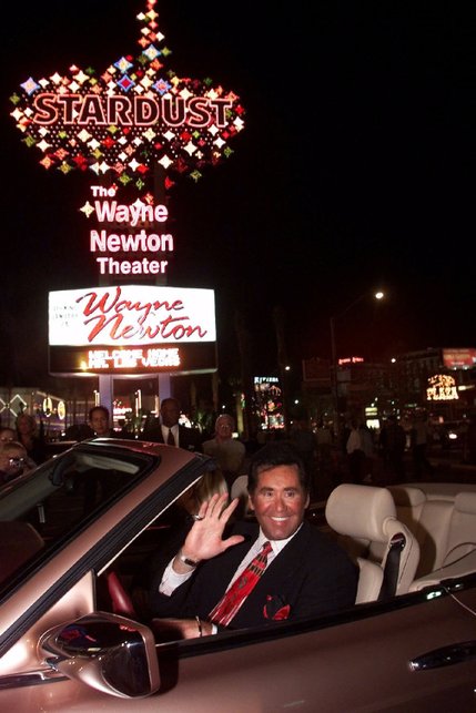 Entertainer Wayne Newton waves beneath the sign at the Stardust hotel-casino after turning on its switch in Las Vegas Thursday, Jan. 20, 2000. The sign lighting ceremony was held to celebrate Wayne Newton's contract with the Stardust that had him headline 40-weeks-a-year until the hotel was demolished in March, 2007.
