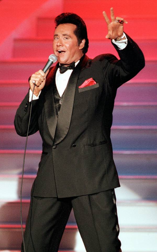 Entertainer Wayne Newton throws up a peace sign during a ...