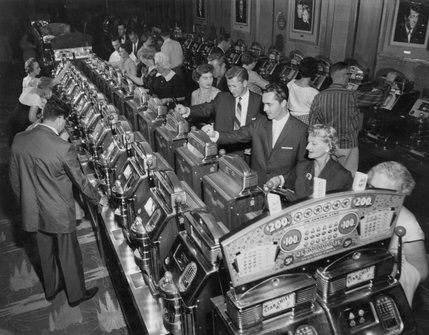 Gamblers play five-cent Star Chief slot machines at the Sands Hotel and Casino during the late 1950s. Portraits of Sammy Davis Jr., Dean Martin and other performers hung along the back wall of the Sands to remind guests of the hotel's celebrity cliental.
