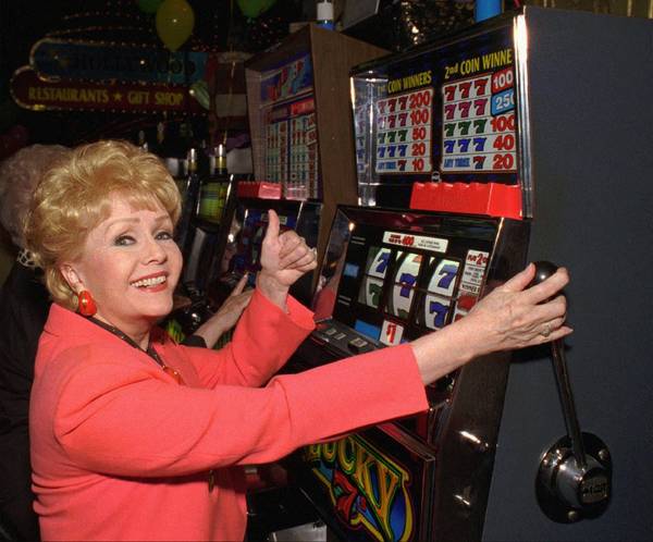 Entertainer Debbie Reynolds pulls the handle of a slot machine ...