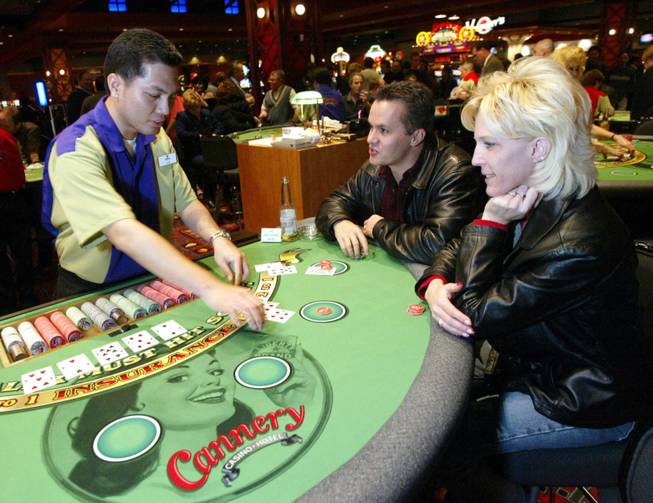Dealer Em Kongmun cleans up after hitting a 21 against T.J. Walton and his wife Cindy during the opening of the Cannery Casino Hotel, Thursday, Jan. 2, 2003. The Cannery is another casino designed for locals, and also includes a buffet, steakhouse and movie theater. 