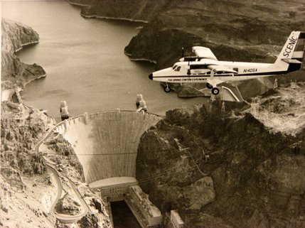 A Grand Canyon tour plane passes just southwest of Hoover Dam. Air tours carry thousands of visitors each year over the dam, the Colorado River and the mountains formed by the river.