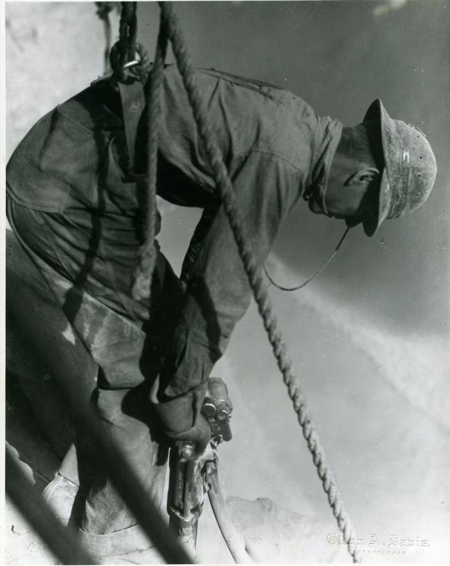  An unidentified worker applies a jackhammer to rock in Boulder Canyon where Hoover Dam stands today. The worker wears a rope harness to keep from falling hundreds of feet from the side of the canyon. The dam stands just over 726 feet tall, and in spite of precautions, 114 people died during construction, according to official records.