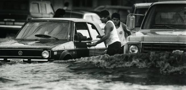 Swamped motorists on Western Avenue attempt to push their stalled vehicle. Before the 400-mile flood control system was installed, the majority of storm drainage was carried along on major roads toward a natural wash. Arterials are still a major component of the system, collecting and moving flood water downstream. 