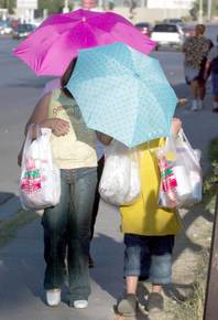 Adrianna Sanchez, 9, left, uses an umbrella to shield herself and her brother Julian Sanchez, 8, from the afternoon sun as they walk along Bonanza Road near 20th Street Sunday, September 28, 2003. Their mother Marissela Martinez does the same as she walks behind them.