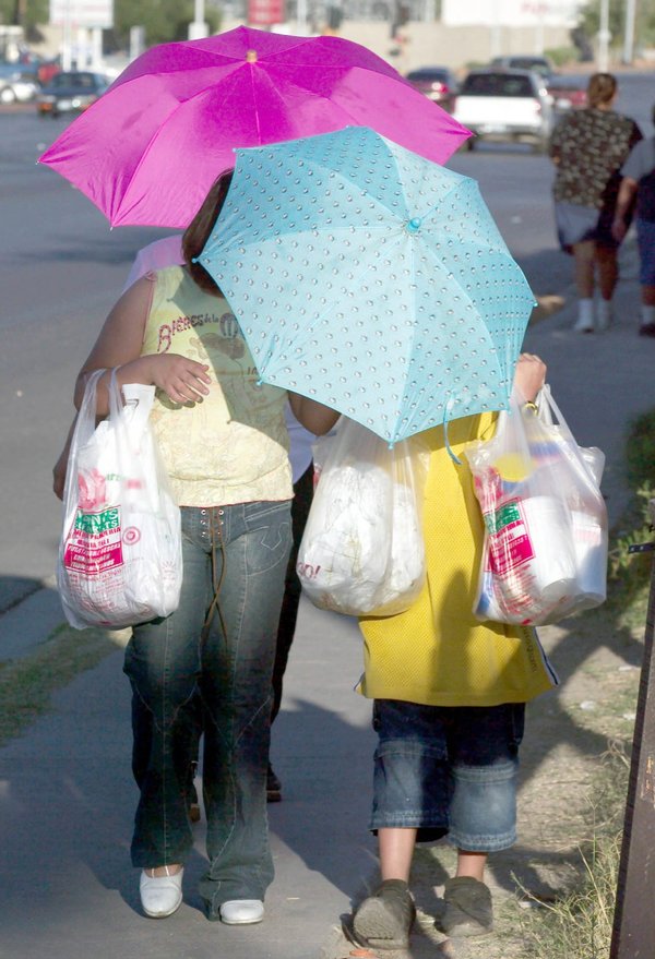 Adrianna Sanchez, 9, left, uses an umbrella to shield herself ...