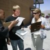 A man who declined to be identified, left, shows a flier to Vance Borton, center, as Andrea Grefrath, right, tries to gather a signature for a ballot initiative at the North Decatur Department of Motor Vehicles (MMV) office Friday. Grefrath is gathering signatures for a ballot measure that would raise gaming taxes to increase funding for public education. The man who declined to be identified represents a group that opposes the initiative. 