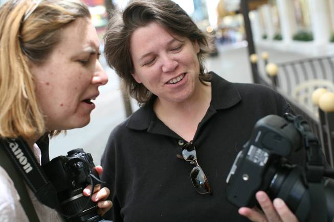 Student Elizabeth Aralica, left, and professor Heather Protz look at a picture on the back of Protz's camera during a group shoot at the Fremont Street Experience.