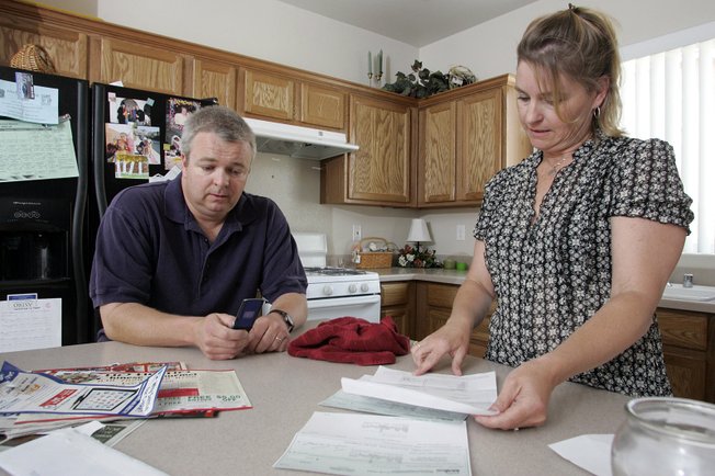 Peggy Montgomery looks over a deposit refund check and documents from a property management company on her last rental home while her husband, Dan, tries to call the management office. The Montgomerys expected $1,500 but received $850 after deductions. After they moved from the home they lived in before that one, they got nothing back. And moving expenses have been about $1,000 each time, they say.